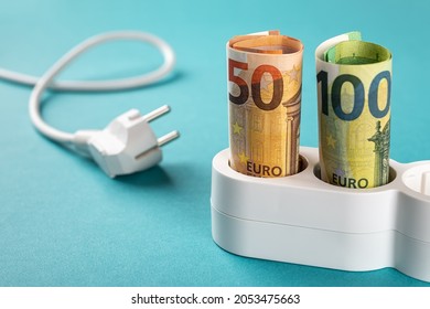 Euro Money Paper Banknotes Plugged Into A White Power Strip Over Blue Bacground. Increasing Cost Of Electricity For Business Users And Residential Customers. Rise In Electricity Prices Concept. 