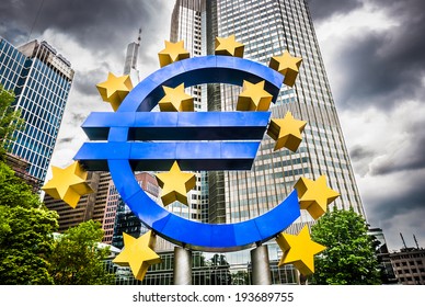 Euro sign at European Central Bank headquarters in Frankfurt, Germany with dark dramatic clouds symbolizing a financial crisis - Shutterstock ID 193689755