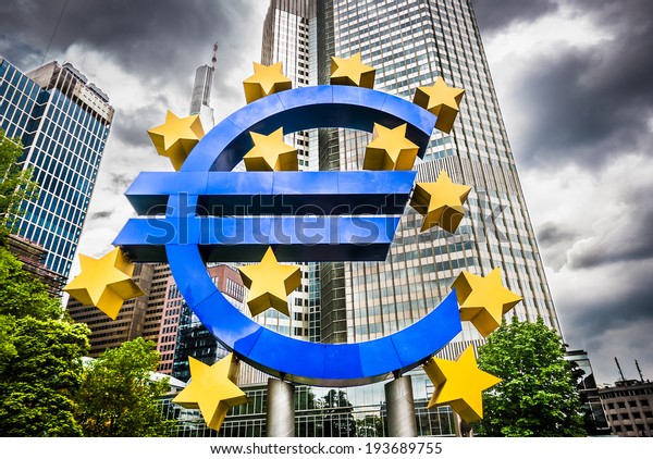 Euro sign at European Central Bank headquarters in\
Frankfurt, Germany with dark dramatic clouds symbolizing a\
financial crisis