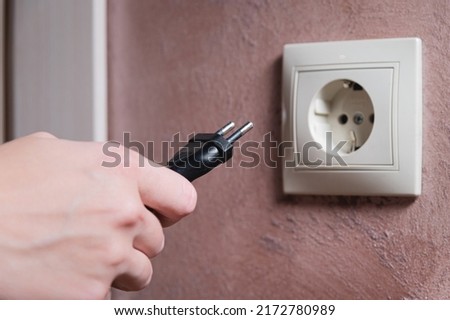 euro socket woman's hand inserts an electric plug into a socket, close-up. cut off the European Union from the energy supply