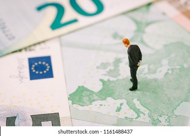 Europe, Brexit Or Britain Economy Or Financial Concept, Miniature Figure Businessman Country Leader Standing On European Map On Euro Banknote Looking At UK, England Map.