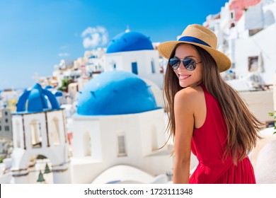 Europe Greece Santorini travel vacation woman on famous santorini Oia island travel destination. Happy young tourist girl in hat and sunglasses relaxing at blue dome church. Summer wanderlust.