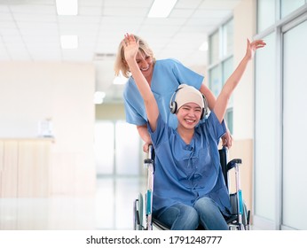 Europe Hospital Caregivers cheer up Asian cancer patient.Metastatic breast cancer with happily smile sit wheelchair listen music by headphone feel freedom at corridor before examination.