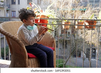 Europe, Italy, Milan - Children Boy Five Years At Home In Quarantine With Mask Plays Music From The Windows - Italian  Flash Mob During Pandemic Of N-cov19 Coronavirus                               