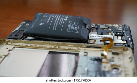 Europe, Kiev, Ukraine - June 2020: Swollen smartphone battery. Damaged smartphone with a faulty battery. Damaged phone on a wooden background. - Shutterstock ID 1751798507