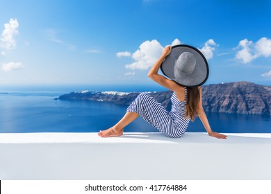 Europe summer vacation travel cruise destination luxury living woman relaxing on outdoor terrace looking at view of Mediterranean Sea and Santorini Oia. Elegant tourist lady in fashion beachwear.