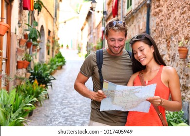 Europe Travel Tourists Couple Looking At Map To Find Directions Walking In Old Streets Of Spanish City Palma In Mallorca, Spain. Asian Woman, Caucasian Man On Cruise Vacation During Summer Holidays.