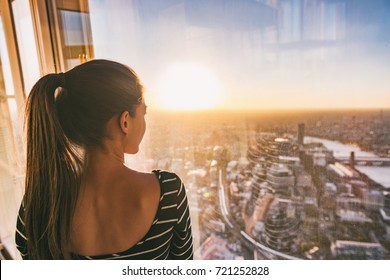 Europe Travel Woman Looking At Sunset View Of London City Skyline From The Window Of Highrise Skyscraper Tower, Famous Tourist Attraction In The U.K.