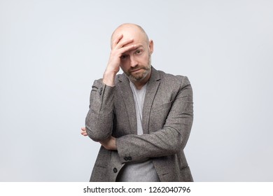 European Bald Man Depressed With Hand On His Head Looking Down