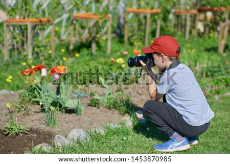 European boy is using the digital camera, training his photo skills.