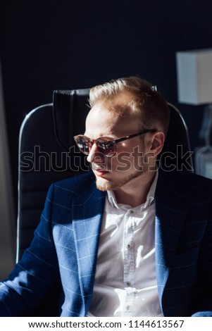 European businessman in sunglasses at workplace in office on a hot day.