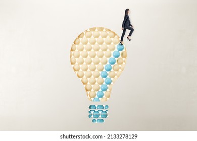 European businesswoman in suit standing on abstract pattern light bulb on light background with mock up place. Idea, growth and success concept