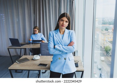 European businesswoman while working in the office. Young serious Millennial brunette woman in a jacket. The concept of freelance and remote work. Modern women's lifestyle