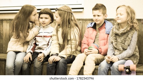 European Children On A Bench Playing Chinese Whispers