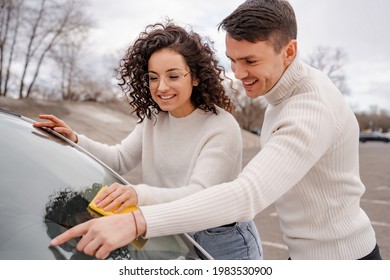 European Couple Cleaning Car Windshield With Rag