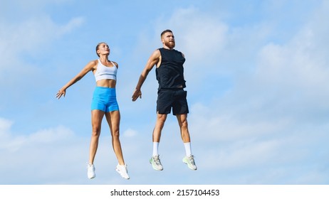 European couple, man and woman jumping high against the blue sky. Healthy lifestyle concept