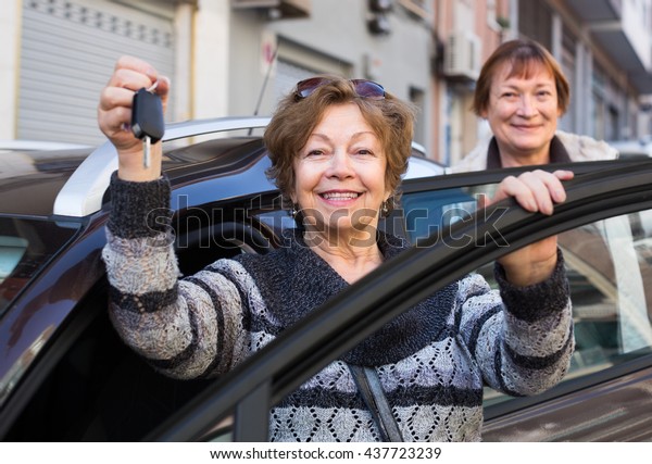 european driver in golden age standing with car\
key outdoor