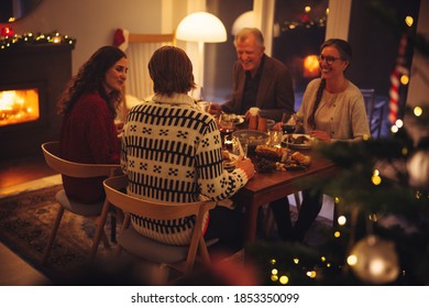 European Family Enjoying Dinner On Christmas Eve. Family Having A Christmas Eve Dinner Together In Warm And Cosy Home.