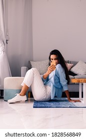 European Fit Brunette Fashion Blogger Woman Sits On Floor In Living Room Near Sofa, Wearing White Jeans And Blue Sweather, And Take Photo Selfie In Mirror   