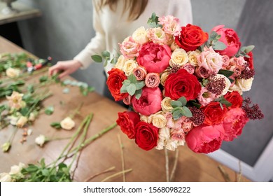 European floral shop concept. Florist woman creates red beautiful bouquet of mixed flowers. Handsome fresh bunch. Education, master class and floristry courses. Flowers delivery. - Shutterstock ID 1568098222
