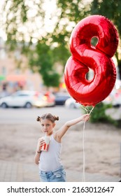 European Girl Child With Balloon In Shape Of 8 With Soda With Straw. Child Drinking Soda Through Straw Summer Outside