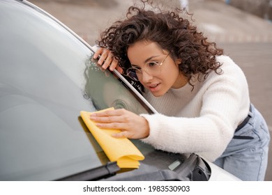 European Girl Cleaning Car Windshield With Rag