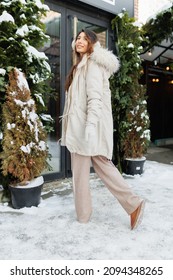 European Girl Posing In A Winter Jacket Against The Backdrop Of A Shop Door Decorated With Fir Branches And Decorations. Christmas Shopping And Holidays.