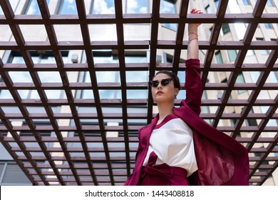 European Girl With Short Haircut Poses Cool In A Red Jacket. Women's Pantsuit Burgundy Color On The Model. Street Photo Lifestyle.