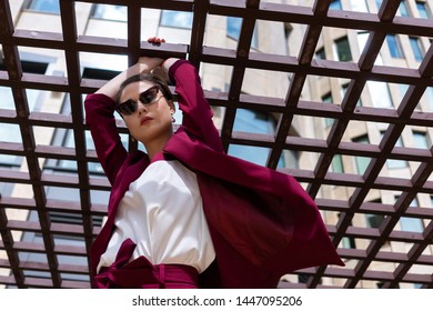 European Girl With Short Haircut Poses Cool In A Red Jacket. Women's Pantsuit Burgundy Color On The Model. Street Photo Lifestyle.