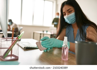 European girl wiping smartphone with napkin while working with colleagues in blurred office. Business people wearing medical masks and gloves. Concept of health protection during Covid-19 pandemic - Powered by Shutterstock