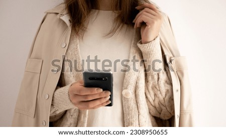 European girl's hand holding a black phone. The girl holds a phone in her hand, dials a number