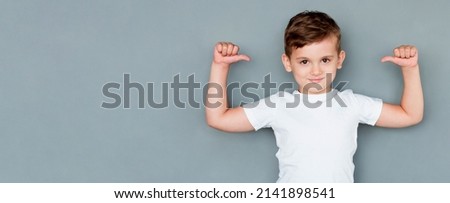 European guy is pro feeling proud and self-assured triumphing, being winner pointing at himself with thumbs tilting head looking confident and assertive in own skills, posing in white t-shirt