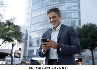 European latin middle age male entrepreneur businessman working on mobile cell phone. Confident mature hispanic senior business man holding smartphone cellphone, using app at busy street at evening - Powered by Shutterstock