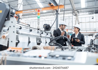 European male engineer and Asian female senior official Owners and business partners of industrial plants Wear a suit to talk and inspect the operation of plastic and steel export production machinery - Powered by Shutterstock