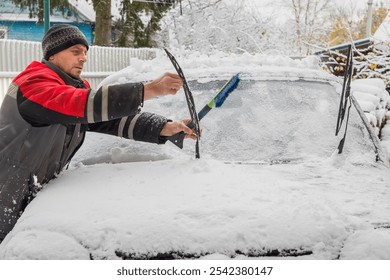 A European man clears snow from the windshield of a car. - Powered by Shutterstock