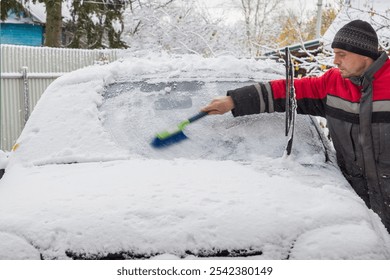 A European man clears snow from the windshield of a car. - Powered by Shutterstock