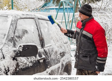 A European man clears snow from the windshield of a car. - Powered by Shutterstock