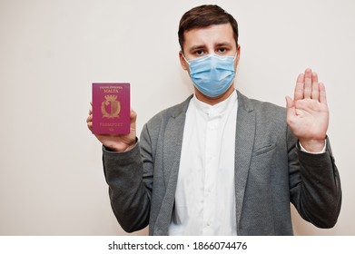 European man in formal wear and face mask, show Malta passport with stop sign hand. Coronavirus lockdown in Europe country concept. 