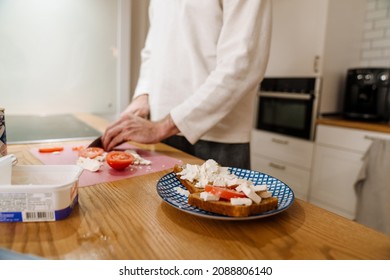 European Man Making Sandwich With Cheese In Kitchen At Home