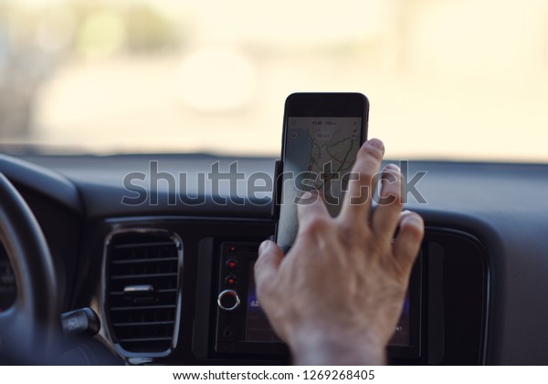 European man is pointing out on the place
at the navigator screen, while driving a car.
