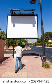 European Man-traveler Walking On Sunny Street By Marrakesh, Morocco. Empty Mockup Of Blank White Billboard On Street. Outdoor Advertising With Copy Space For Pedestrians And Drivers