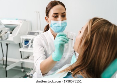 European mid dentist woman in face mask working in dental clinic - Shutterstock ID 1938573151