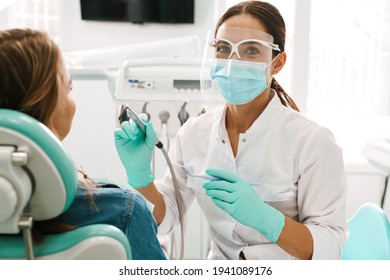 European mid pleased dentist woman in face mask working in dental clinic - Powered by Shutterstock