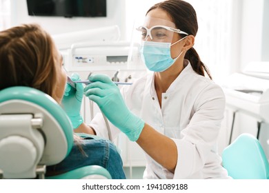 European mid pleased dentist woman in face mask working in dental clinic - Shutterstock ID 1941089188