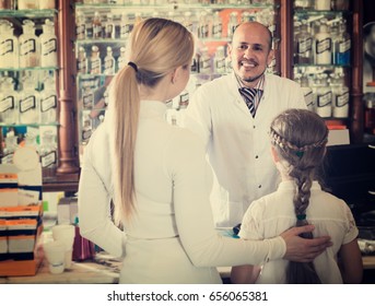 european pharmacist standing with a cash desk in the pharmacy and helping customers