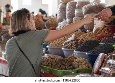 European She-tourist Buys Sweets And Nuts On The Food Market (bazaar). Bukhara, Uzbekistan, Central Asia.