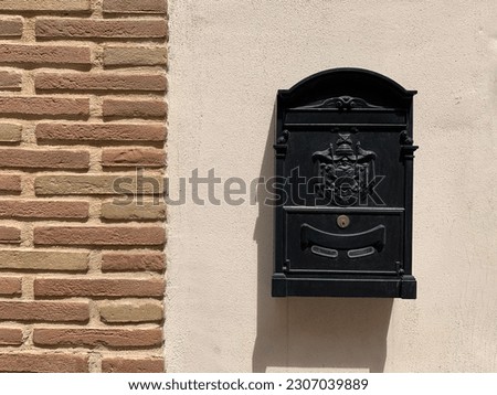 European style black mailbox stuck on a cement wall