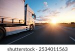 European truck driving on the asphalt road in rural landscape at sunset. Transportation and cargo concept.