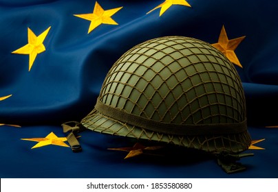 European Union Army, Military Uniform And Defense Of Europe Concept With Soldier Helmet With Camouflage Pattern And The EU Flag In The Background