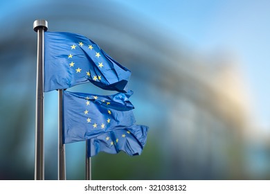 European Union flags in front of the blurred European Parliament in Brussels, Belgium - Shutterstock ID 321038132